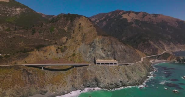 カリフォルニア州の海岸線で山を結ぶ道路 青い澄んだ空の背景にある険しい岩の美しい景色 — ストック動画