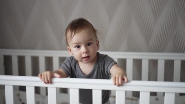 Schöner Junge Steht Seinem Kinderbett Und Hält Sich Den Handläufen — Stockvideo
