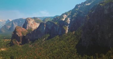 Yosemite Ulusal Parkı 'nda çok güzel kaya oluşumları var. Dağları aşan çam ağacı ormanı. Güneşli bir gün Gökyüzü arkaplanı açık.