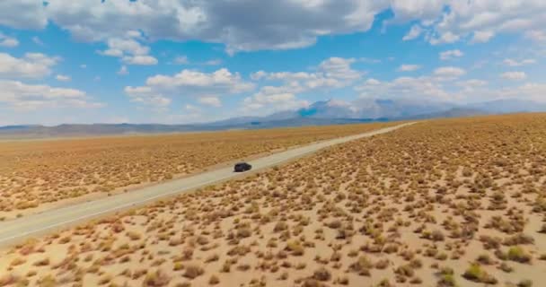 赶上一辆黑色轿车在空旷的路上穿过沙漠 美丽的蓝天 白云柔和 — 图库视频影像