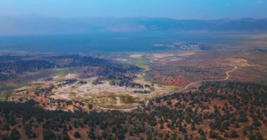 California, ABD 'de sıradışı Travertine Kaplıcaları manzarasının güzel manzarası. Arkaplanda derin mavi sisli dağlar. Hava görünümü.