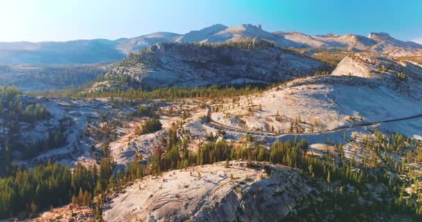 高大的白色岩石上生长着一些松树 路上有车绕着山 美国加利福尼亚约塞米蒂国家公园阳光普照 — 图库视频影像