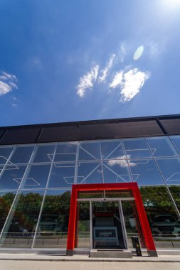 Kırmızı kapısı ve cam duvarı olan modern binanın girişi.