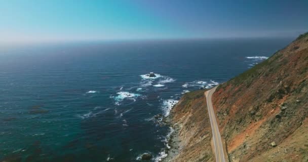 岩石海岸 悬崖上有高速公路 美丽无尽的蓝色太平洋与蔚蓝的天空交织在一起 空中景观 — 图库视频影像