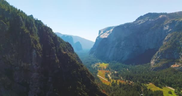 アメリカ合衆国カリフォルニア州ヨセミテ国立公園の崖の岩の間の緑の晴れた谷 澄んだ空を背景にした空中観察 — ストック動画