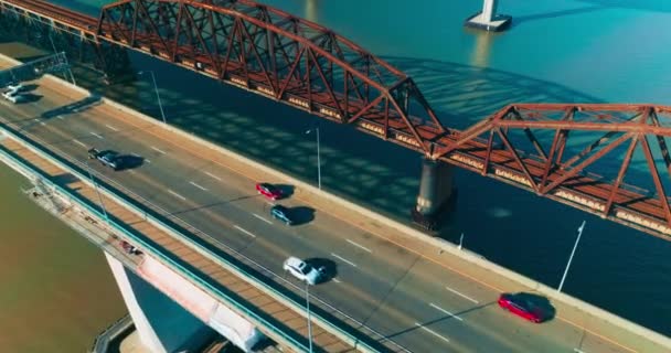 4車線の片道道路を備えたブリッジ 高速道路で移動するクイックカー 横の金属製の錆ついた鉄道橋 上からの眺め — ストック動画