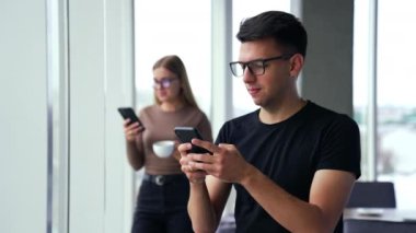 Ofiste öğle yemeği molasında modern aletleri kullanmak. Telefon bağımlısı insanlar konsepti. Görüntü arkaplanındaki panoramik pencereler.