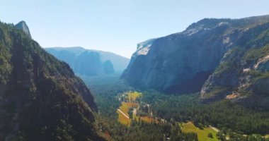 Dağlarda ve vadide çam ağaçları yetişiyor. Yosemite Ulusal Parkı, Kaliforniya, ABD 'de kayalardan oluşan güneş ışığı manzarası. Hava görünümü.