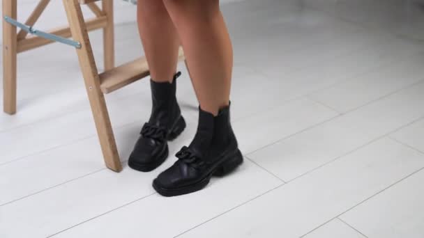 模特儿走到木梯子前 坐着展示鞋袜 黑色正方形靴子在工作室的展示 — 图库视频影像
