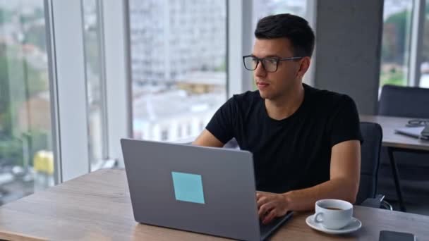 Gözlüklü Siyah Tişörtlü Dalgın Genç Adam Ofiste Dizüstü Bilgisayarın Önünde — Stok video