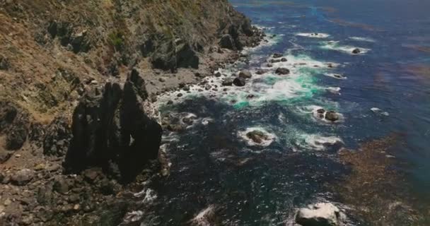 阳光灿烂的日子 飞越加州危险的岩石海岸 浪花涌向海岸线 顶部视图 — 图库视频影像