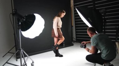 Kameranın önünde poz veren, şık ayakkabı ve çanta sergileyen bir kız. Stüdyoda çalışan bir fotoğrafçının sahne arkasında..