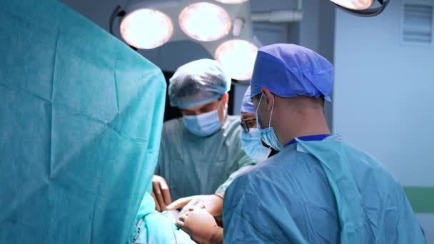 男性外科医チームは 実施された手順に焦点を当てました 青いユニフォーム キャップ マスクのドクターは 手とツールで動作します — ストック動画
