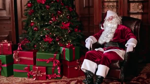 Pensive Santa Claus Sitting Comfortable Chair Christmas Tree Lots Presents — Stock Video