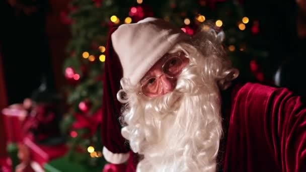 Beyaz Sakallı Gözlüklü Noel Baba Koltuğa Yaslanıyor Arkaplanda Işıkları Olan — Stok video