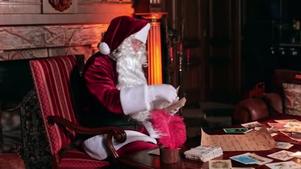 Santa Claus Escribiendo Las Tarjetas Navidad Sentado Cerca Chimenea Acogedor — Vídeos de Stock