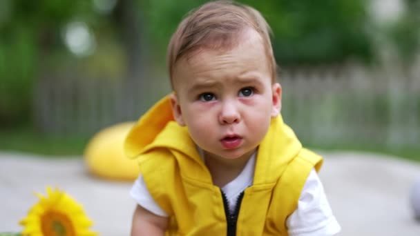 小さな愛らしいコーカサス人の赤ん坊の少年は 屋外で時間を過ごしています カメラにまっすぐ見えるかわいいトッドラー クローズアップ — ストック動画