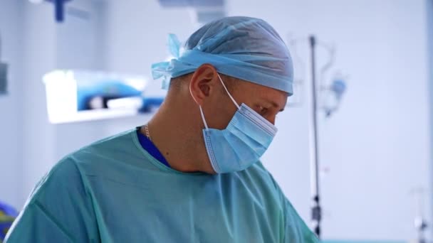 男性外科医は 実施された手術に焦点を当てました プラスチック手術中に右手で積極的に動くマスクの医師 — ストック動画