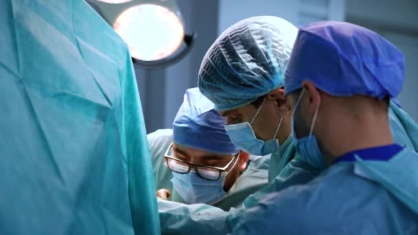 男性の医師は現代の外科室の医療処置に焦点を当てました 手順で密接に協力するマスクの外科医 — ストック動画