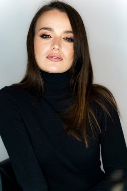 Uzun kahverengi saçlı, siyah balıkçı yakalı güzel bir kadın..