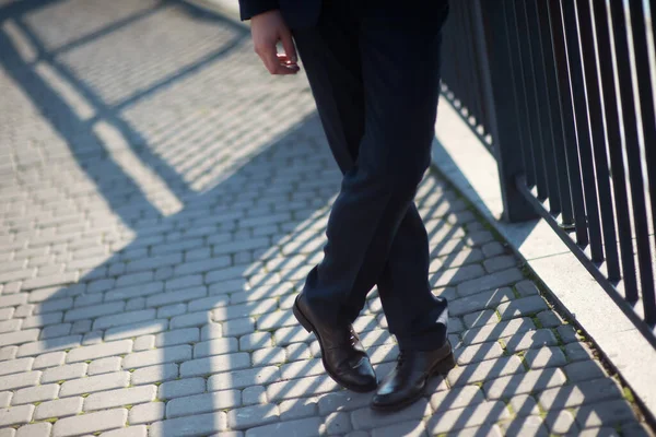 Man in suit walks along brick sidewalk.