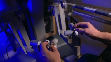 Cerrahın erkek elleri fütüristik ekipmanların saplarını tutuyor. Doktor Da Vinci robotunun kollarını yönetiyor. Kapat..