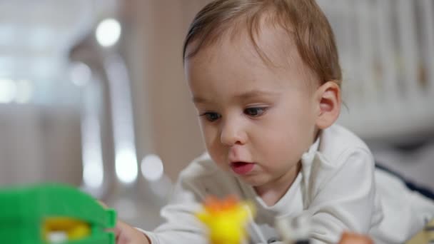 可爱的小宝宝把玩具放在肚子上玩 可爱的幼儿被游戏完全吸引住了 靠近点模糊的背景 — 图库视频影像