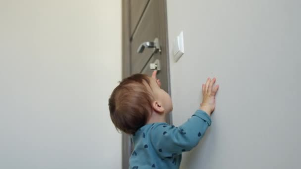 Παιδί Ενός Έτους Στέκεται Δίπλα Στον Τοίχο Προσπαθώντας Φτάσει Διακόπτη — Αρχείο Βίντεο