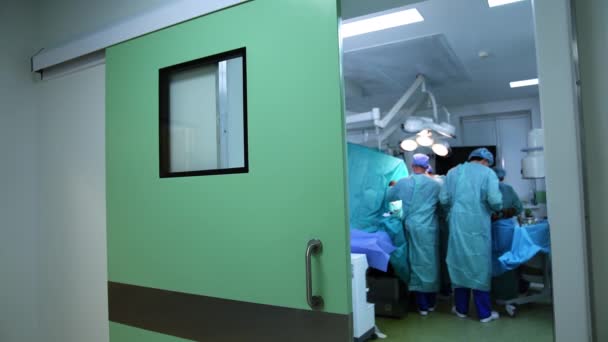 Amplias Puertas Abrían Moderno Quirófano Tres Cirujanos Trabajan Mesa Operaciones — Vídeo de stock