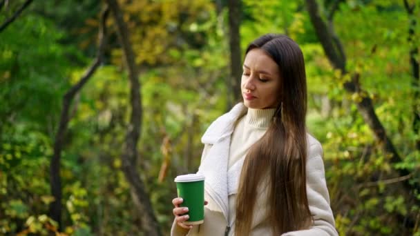 深沉沉稳的长发女士在秋天的公园里度过了一段时光 女人正享受着阳光穿过树林 模糊的背景 — 图库视频影像