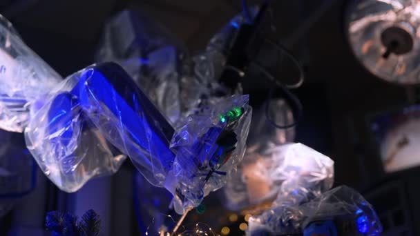暗い手術室で移動するプラスチックで覆われた未来的なロボットアーム 操作テーブルのクリスマスの装飾 — ストック動画