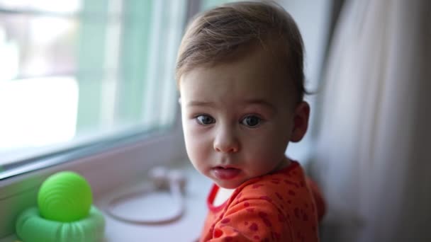 Lovely Caucasian Kid Standing Window Sill Baby Makes Wry Face — Stock Video