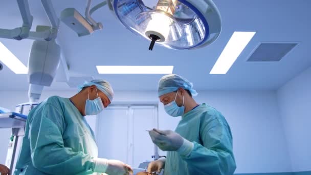 Zespół Lekarzy Pracujących Nowoczesnej Sali Operacyjnej Pod Dużą Okrągłą Lampą — Wideo stockowe