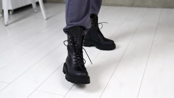 黑色的军靴 鞋带在模特的腿上 在演播室的白色地板上 女人穿着时髦的鞋子走路 俯瞰近景 — 图库视频影像