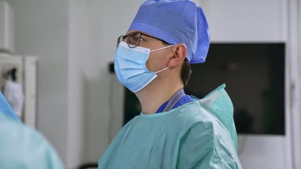 外科医生专业地盯着屏幕 对他的同事们说了些什么 在现代诊所执行手术的医生队伍 — 图库视频影像