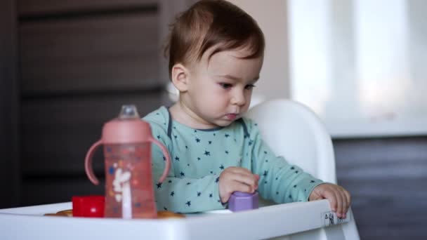 可爱的小男孩坐在喂食椅上 白种人小孩 满脸污迹 玩玩具 模糊的背景 — 图库视频影像