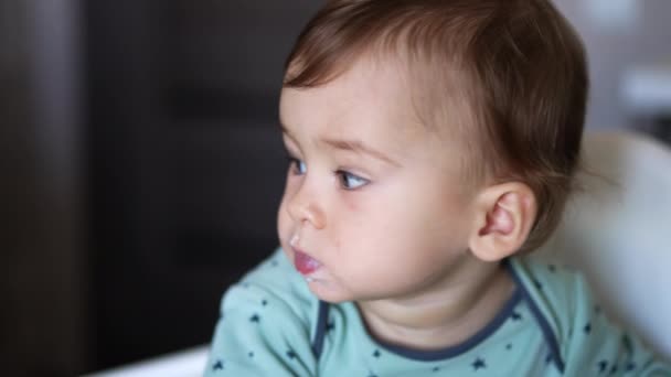 可爱的孩子嘴边有吃的一个婴儿在喂奶的过程中静静地坐着的画像 靠近点模糊的背景 — 图库视频影像