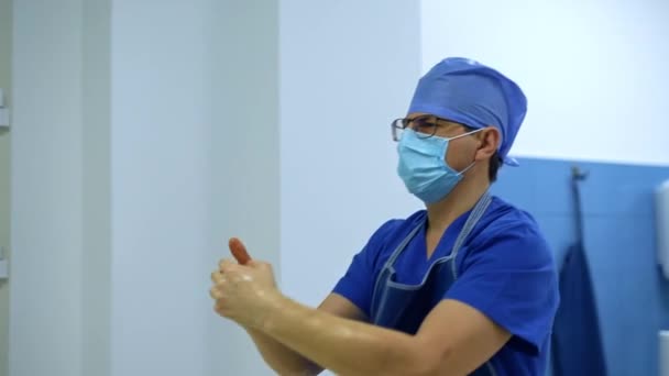 外科医は防腐剤で覆われた手をつないで歩いています 外科手術の準備をする男性の医師 — ストック動画