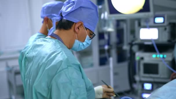 現代の診療所で2人の外科医が手術を行っている チーフ外科医は看護師に道具を与え 別の器具を取り戻す — ストック動画