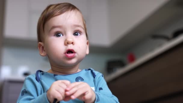 可爱的宝宝穿着蓝色衬衫坐在室内地板上 冷静点 白人孩子正忙着他手里拿着的东西 靠近点 — 图库视频影像