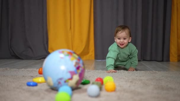 Весёлый Улыбающийся Малыш Ползает Полу Активный Счастливый Ребенок Бросает Мяч — стоковое видео