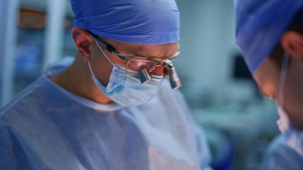 Přední Chirurg Nosí Brýle Zaměřením Chirurgii Mladší Lékař Který Asistuje — Stock video