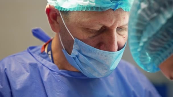 患者を見下ろす外科マスクの大人の男性医師 経験豊富な外科医が仕事に集中しました クローズアップ — ストック動画