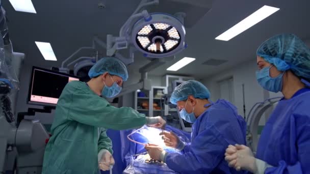 手術中の神経外科医を支援する2つの医師 メインドクターにフォースを渡す男性アシスタント バックドロップの高度な機器 — ストック動画