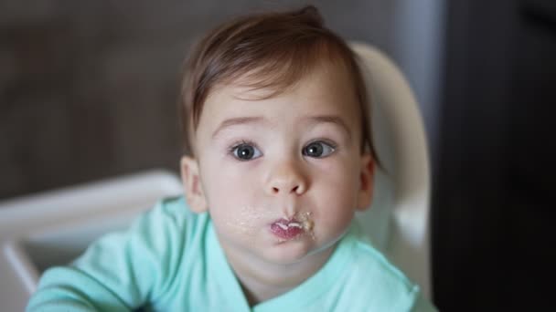 Słodkie Szare Dziecko Jedzące Owsiankę Dzieciak Pełnymi Ustami Patrzy Kamerę — Wideo stockowe