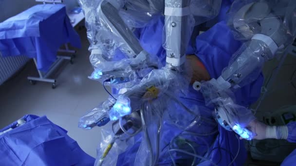 患者は現代の手術室でロボットの革新的な装置によって操作されます マニピュレータアームは 医師と一緒に医療機器を適用する — ストック動画