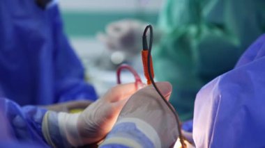 Cihaz aletlerini kullanan eldivenli eller. Doktor iki elinde de ameliyat aletleri tutuyor. Kapatın. Bulanık arkaplan.
