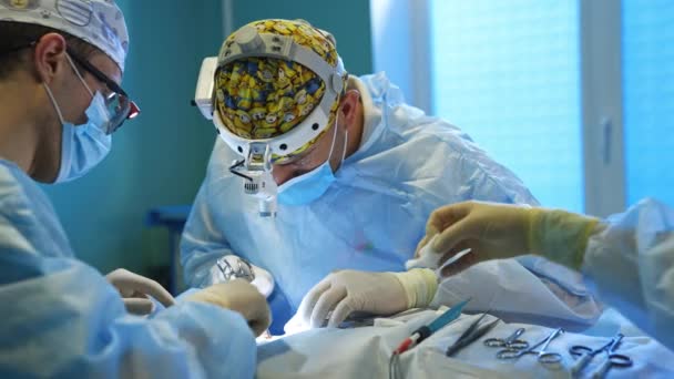 Biali Chirurdzy Latarkami Głowach Wykonujący Operacje Ręka Pielęgniarki Umieszcza Narzędzia — Wideo stockowe