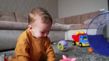 Büyük salonda neşe içinde oynayan sevimli bir çocuk. Güzel bebek oyuncağa bakıyor ve içeride mutlu bir şekilde gülüyor..