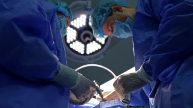 Beyin cerrahı, hemşireye şırınga tutarken tüplü cihaz kullanıyor. Cerrahi odasındaki modern yuvarlak lambanın altında çalışan sağlıkçılar. Düşük açı görünümü.